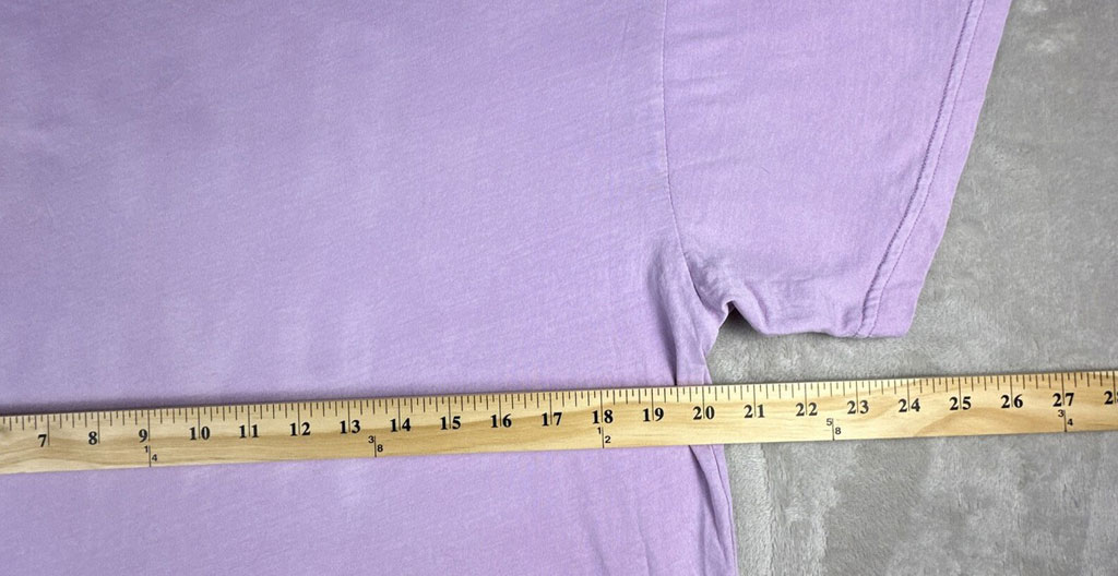 Gros plan sur des mains mesurant avec précision le placement d'un logo sur t-shirt professionnel à l'aide d'un mètre ruban dans un atelier lumineux